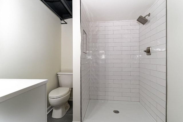 bathroom with a tile shower, vanity, toilet, and tile patterned floors