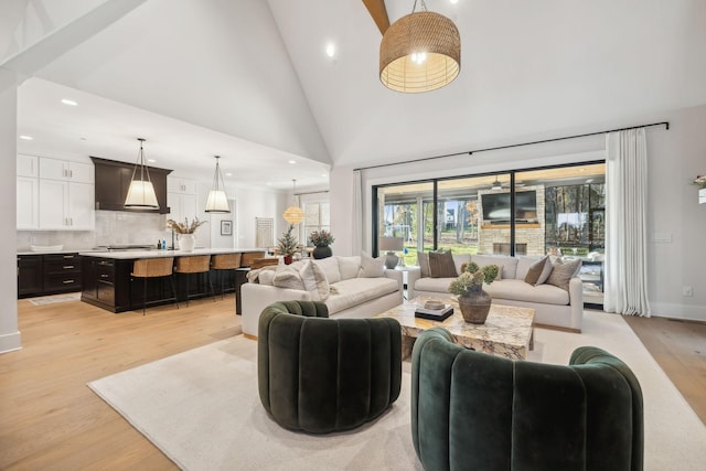 living room featuring high vaulted ceiling and light hardwood / wood-style flooring