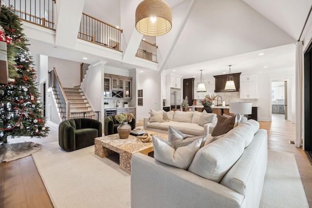 living room with light hardwood / wood-style floors, high vaulted ceiling, and sink