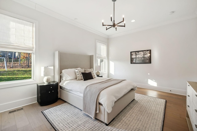 bedroom with multiple windows, crown molding, wood-type flooring, and a notable chandelier