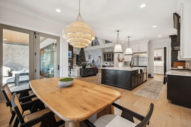 dining room featuring a chandelier, light hardwood / wood-style flooring, crown molding, and sink