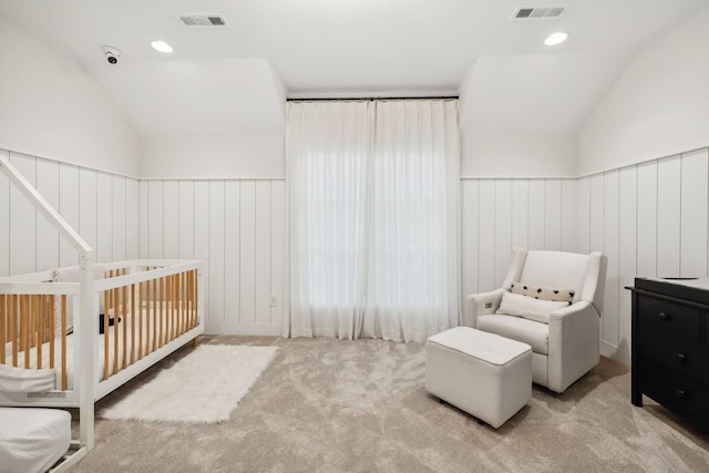 bedroom featuring light carpet, vaulted ceiling, a nursery area, and wood walls