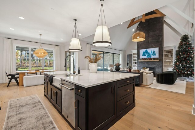 kitchen featuring a large fireplace, sink, hanging light fixtures, and light wood-type flooring