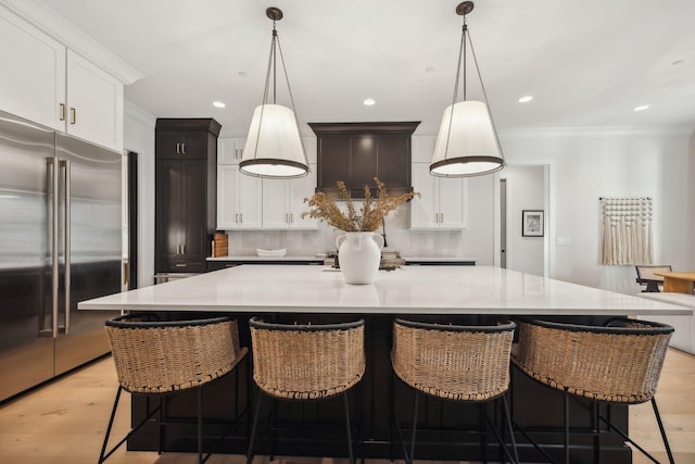 kitchen featuring a large island, tasteful backsplash, hanging light fixtures, and built in refrigerator