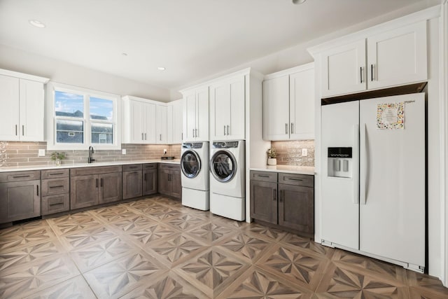 clothes washing area featuring cabinets, light parquet floors, washer and clothes dryer, and sink