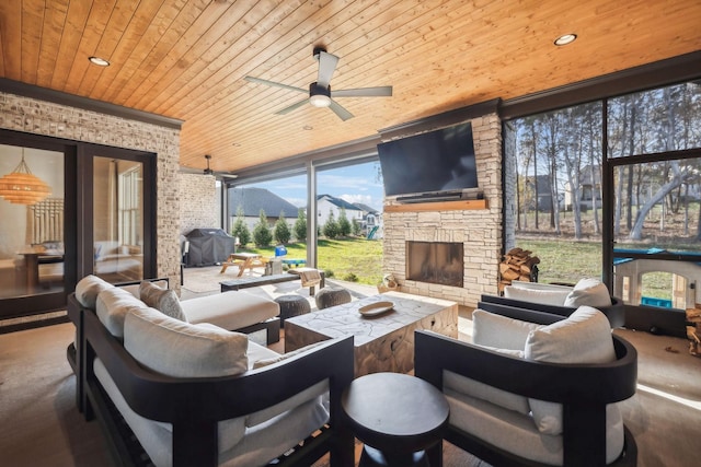 interior space with an outdoor living space with a fireplace, ceiling fan, and a grill