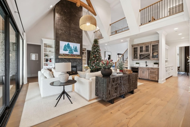 living room featuring wine cooler, light hardwood / wood-style flooring, high vaulted ceiling, and a premium fireplace