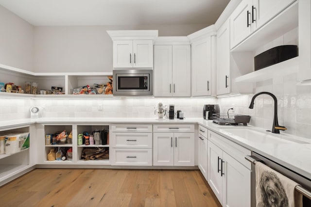 kitchen featuring white cabinetry, sink, tasteful backsplash, appliances with stainless steel finishes, and light wood-type flooring