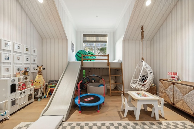 playroom with wood walls, light hardwood / wood-style floors, and crown molding