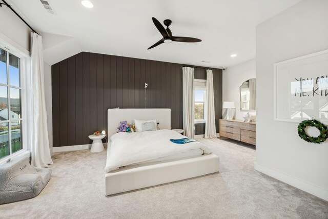 carpeted bedroom featuring ceiling fan, wood walls, and vaulted ceiling