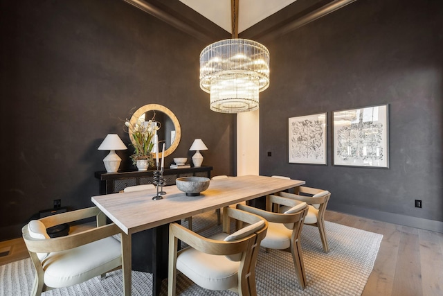 dining space featuring hardwood / wood-style flooring, a notable chandelier, and beam ceiling