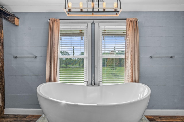 bathroom with a washtub, wood walls, and hardwood / wood-style flooring