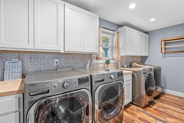 laundry room featuring washer and dryer, cabinets, and light wood-type flooring