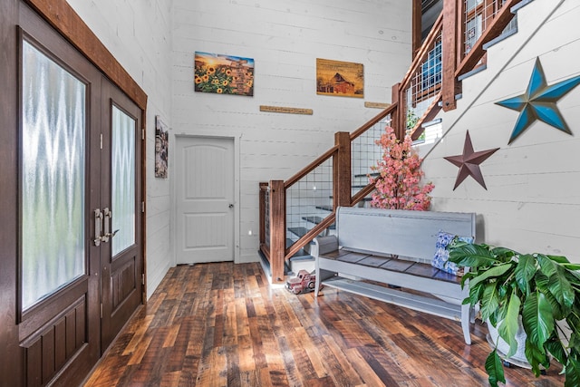 foyer featuring french doors, dark hardwood / wood-style flooring, and wooden walls