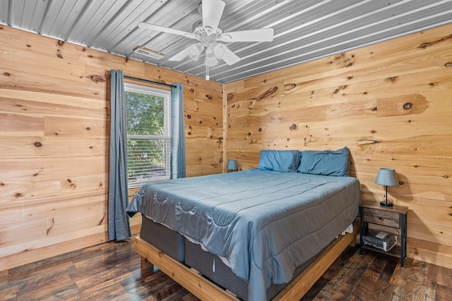 bedroom with ceiling fan, wood walls, and dark hardwood / wood-style floors