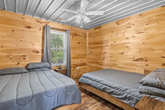 bedroom featuring hardwood / wood-style floors, wood walls, and ceiling fan