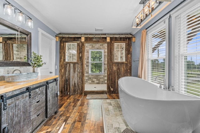 bathroom with vanity, hardwood / wood-style floors, a healthy amount of sunlight, and a tub