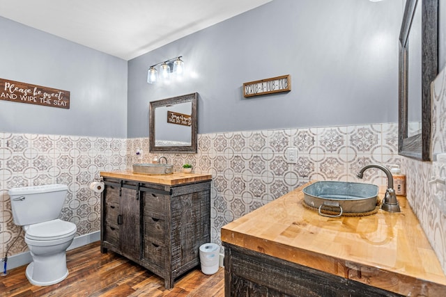 bathroom with tile walls, toilet, hardwood / wood-style floors, and vanity