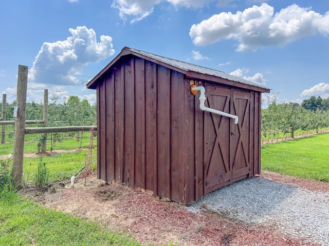 view of outbuilding with a rural view and a lawn