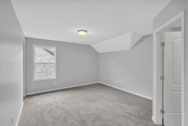 additional living space featuring lofted ceiling and light carpet