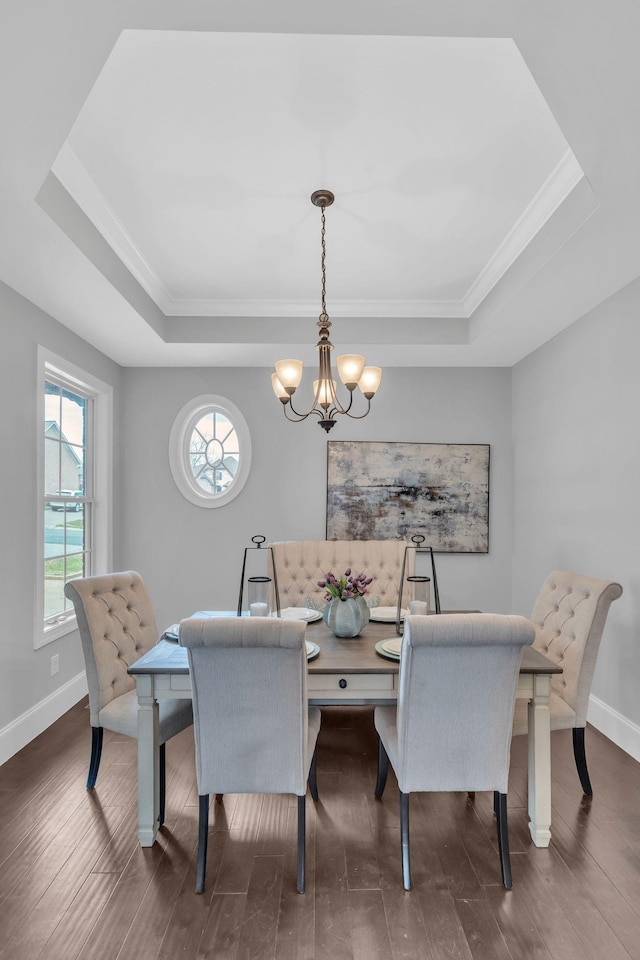 dining area with dark hardwood / wood-style flooring, a tray ceiling, and an inviting chandelier