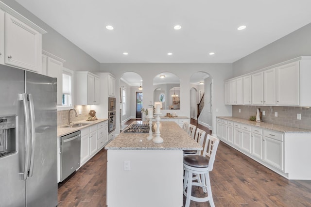 kitchen with dark hardwood / wood-style flooring, stainless steel appliances, sink, white cabinets, and a kitchen island