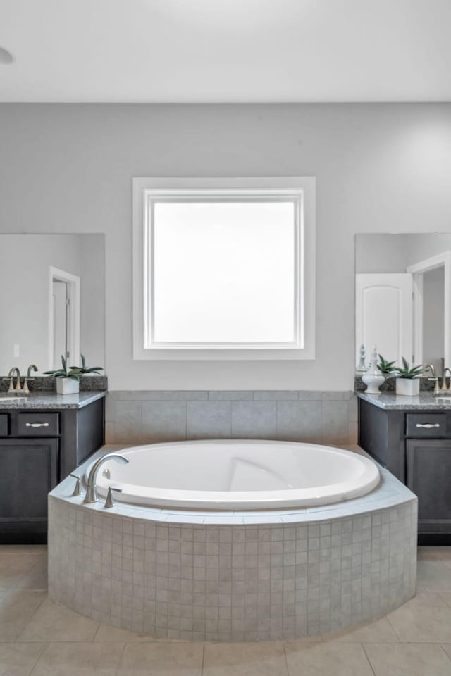 bathroom featuring plenty of natural light, vanity, and a relaxing tiled tub