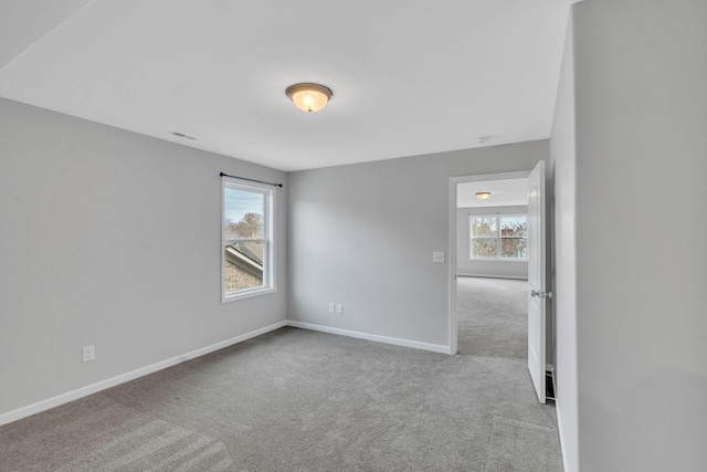 unfurnished room featuring light colored carpet and a wealth of natural light