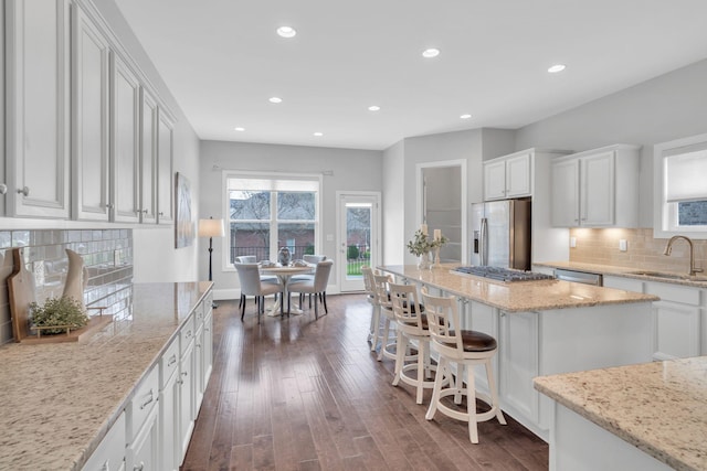 kitchen with light stone countertops, stainless steel appliances, sink, dark hardwood / wood-style floors, and white cabinetry