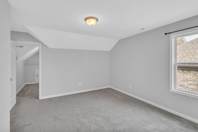 additional living space featuring light colored carpet and lofted ceiling