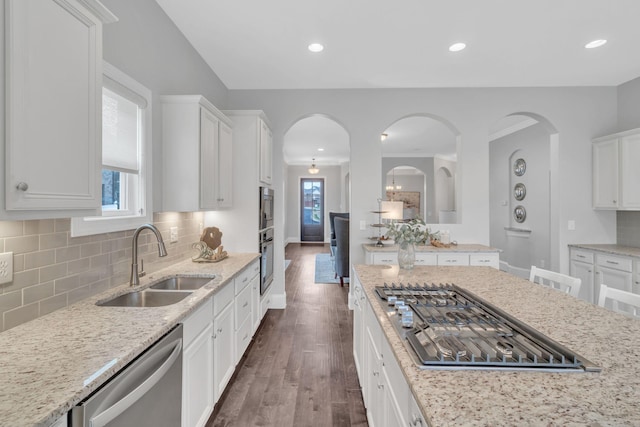 kitchen featuring appliances with stainless steel finishes, dark hardwood / wood-style flooring, light stone counters, sink, and white cabinetry