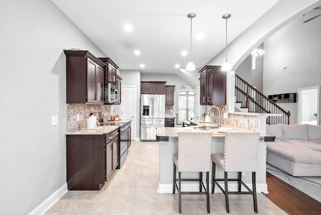 kitchen featuring sink, vaulted ceiling, decorative light fixtures, kitchen peninsula, and stainless steel appliances