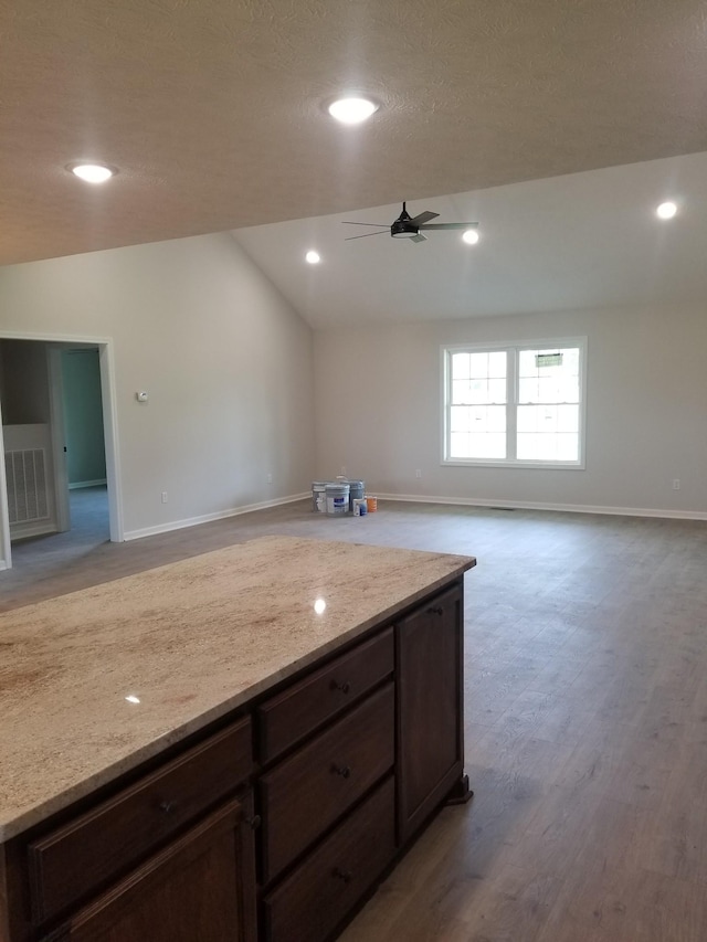 kitchen with light stone counters, light hardwood / wood-style flooring, and vaulted ceiling