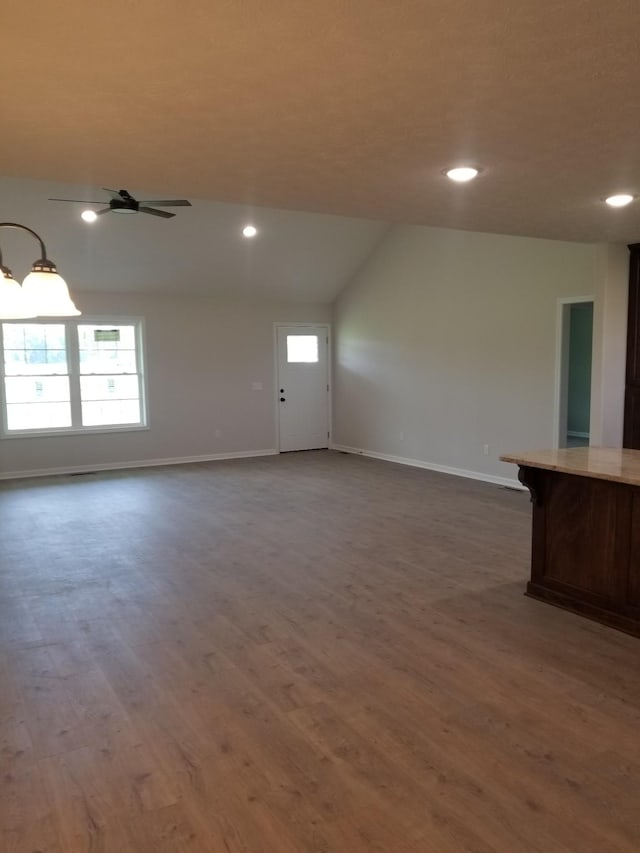 unfurnished living room with ceiling fan, dark wood-type flooring, and vaulted ceiling