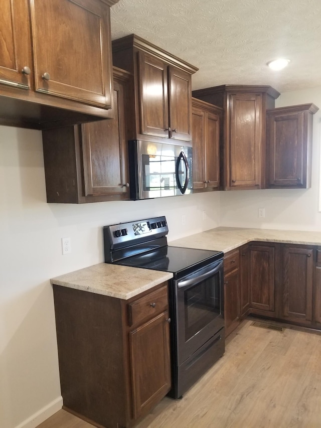 kitchen featuring light stone counters, light hardwood / wood-style flooring, black / electric stove, a textured ceiling, and dark brown cabinets