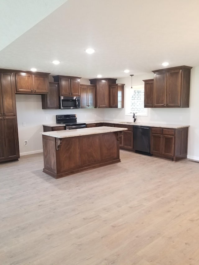 kitchen with black appliances, decorative light fixtures, sink, and light hardwood / wood-style flooring