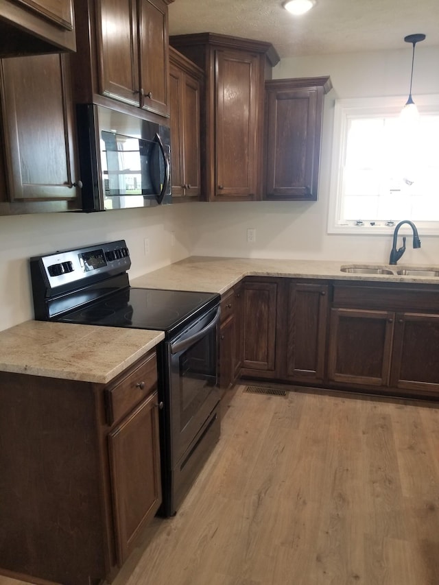 kitchen with light wood-type flooring, black range with electric stovetop, sink, and dark brown cabinetry