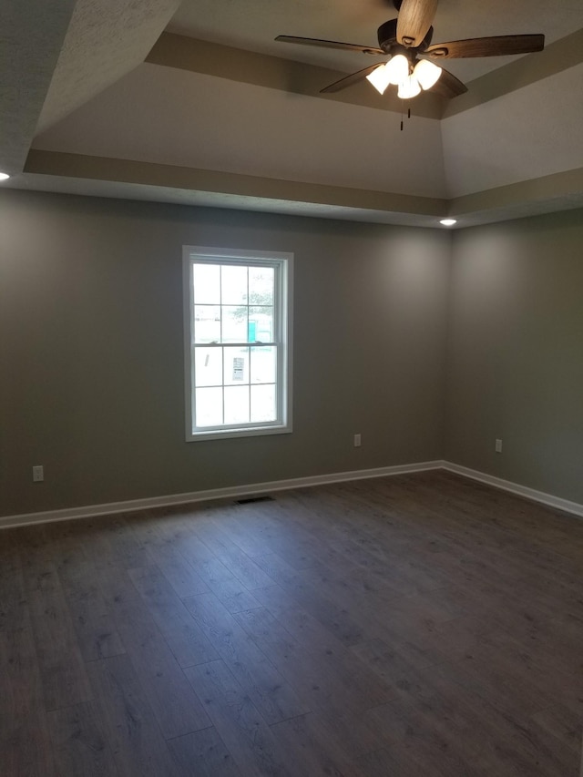 spare room featuring dark hardwood / wood-style flooring, a raised ceiling, and ceiling fan