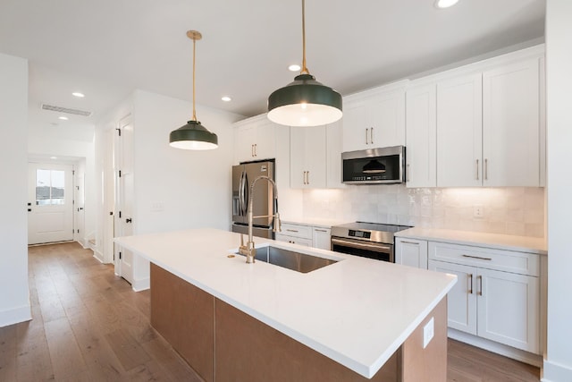 kitchen featuring white cabinetry, an island with sink, and stainless steel appliances