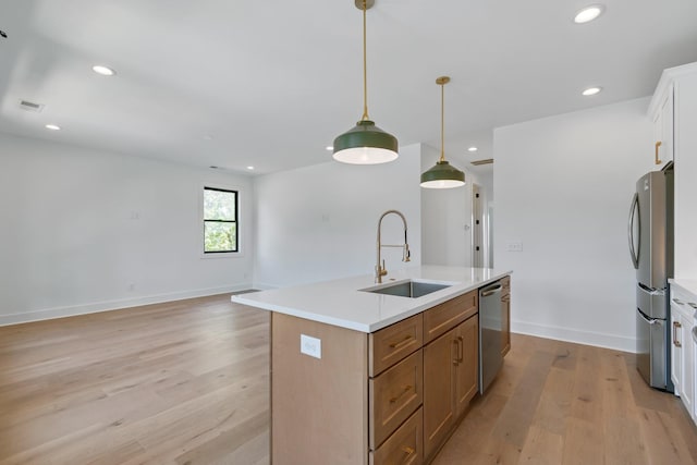 kitchen featuring appliances with stainless steel finishes, sink, pendant lighting, white cabinets, and an island with sink