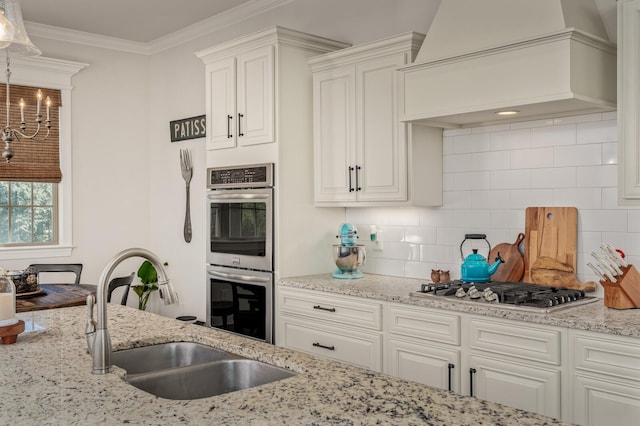 kitchen with backsplash, white cabinets, sink, custom range hood, and stainless steel appliances