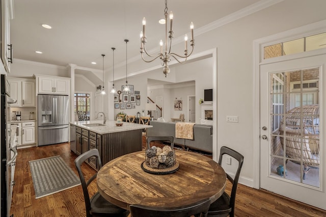 dining area with dark hardwood / wood-style flooring, crown molding, a notable chandelier, and sink