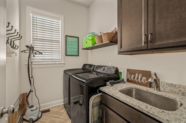 laundry room with sink, light parquet floors, cabinets, and independent washer and dryer