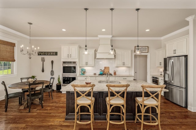 kitchen featuring hanging light fixtures, sink, an island with sink, appliances with stainless steel finishes, and dark hardwood / wood-style flooring