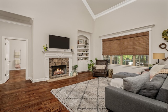 living room featuring dark hardwood / wood-style floors, crown molding, built in features, and a fireplace