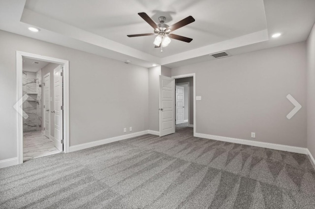 unfurnished bedroom with visible vents, baseboards, a raised ceiling, and carpet