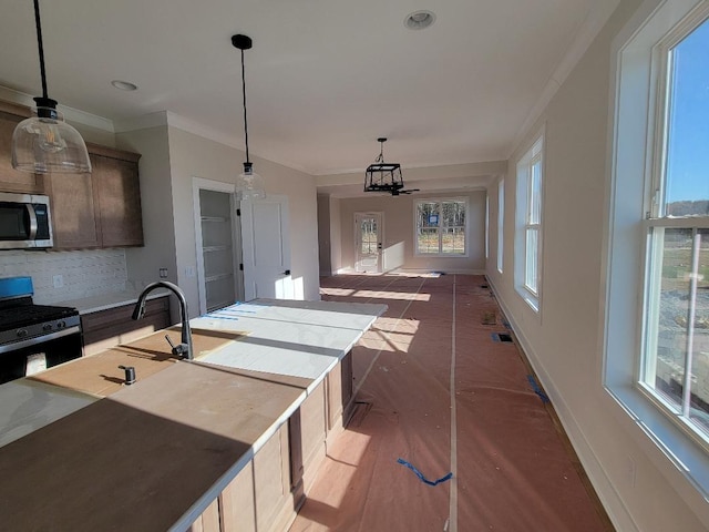 kitchen with sink, stainless steel appliances, crown molding, decorative light fixtures, and decorative backsplash