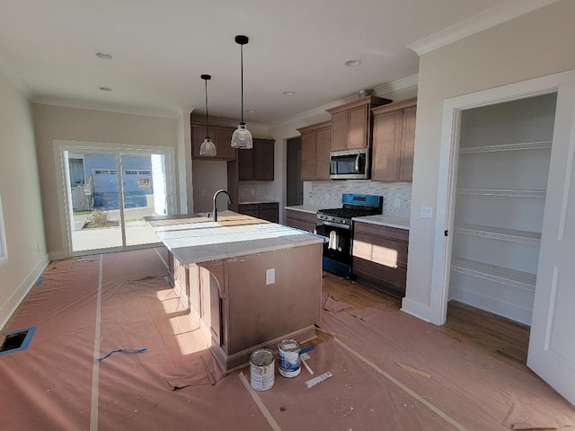 kitchen with pendant lighting, backsplash, ornamental molding, an island with sink, and black range with gas cooktop