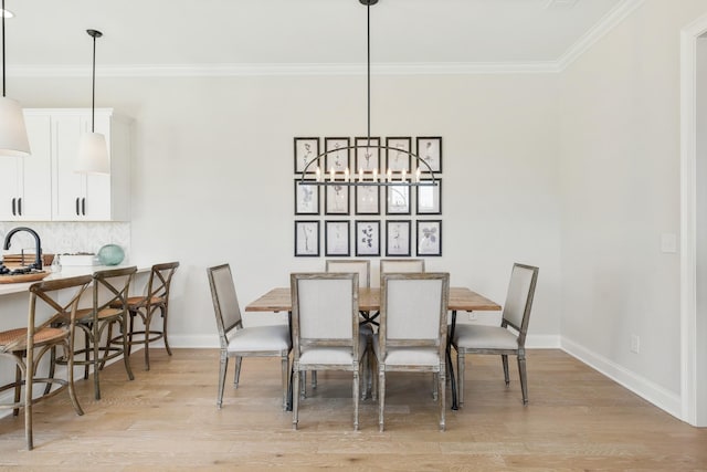 dining area with a chandelier, sink, crown molding, and light hardwood / wood-style flooring