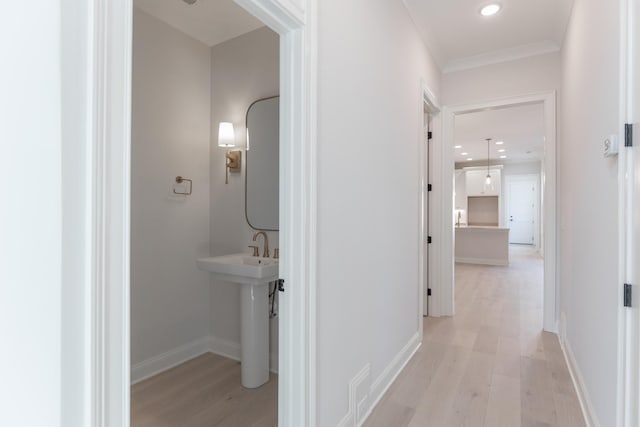 hall with recessed lighting, baseboards, light wood-type flooring, and a sink